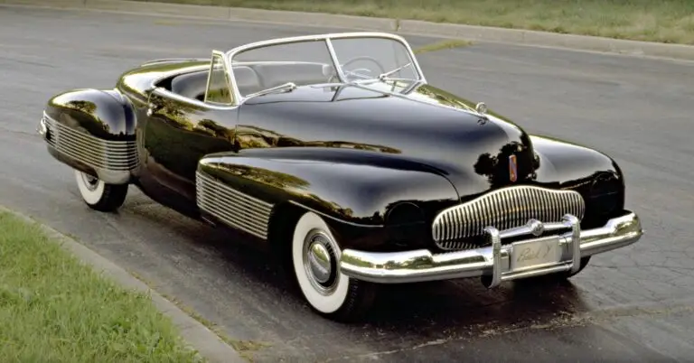 Sleek black classic convertible with chrome details parked on a road, showcasing vintage automotive design and style.