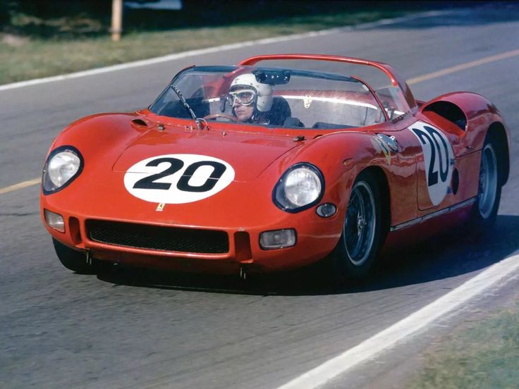 Vintage red race car on track, number 20, driven by helmeted racer, showcasing classic motorsport style.