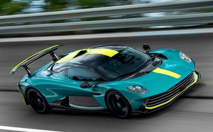 Aston Martin Valhalla begins final testing ahead of production in Q2 2025 - Engine Stories Teal and yellow high-performance sports car speeding on a road, showcasing sleek design and aerodynamic features.