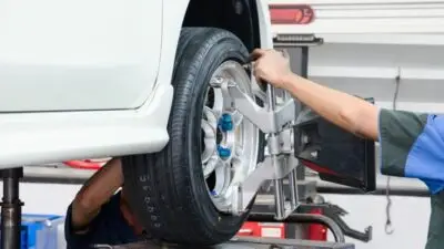 Mechanic adjusting car wheel alignment in auto repair shop for optimal performance and safety.