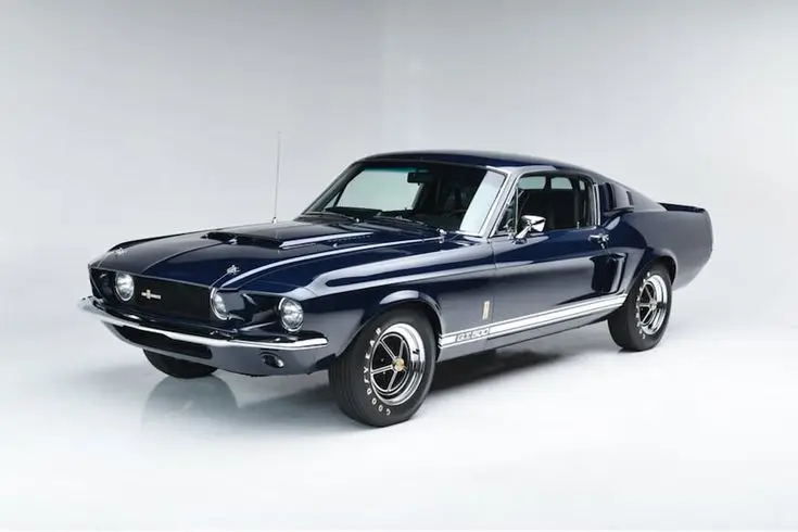 Classic dark blue 1967 Ford Mustang GT500 fastback on a white background, showcasing iconic vintage automotive design.