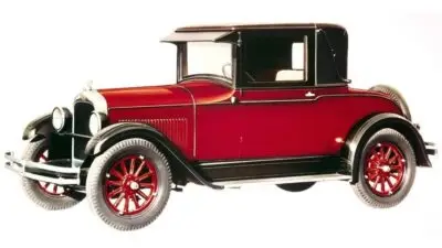 Classic vintage car, red coupe with black top and detailed spoked wheels, showcasing early 20th-century automotive design.