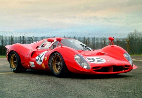 Red vintage race car with number 92 on the side, parked on asphalt. Classic design with aerodynamic curves and a sporty look.