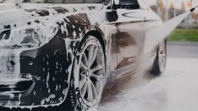Luxury car getting thorough wash with soap and water, emphasizing cleanliness and shine. Perfect car care and maintenance.