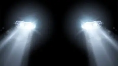 Car headlights shining brightly in the dark, illustrating illumination and safety in nighttime driving conditions.