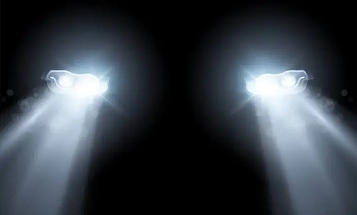 Car headlights shining brightly in the dark, illustrating illumination and safety in nighttime driving conditions.
