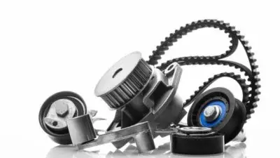 Close-up of automotive engine parts including timing belt and pulleys on white background, showcasing precision engineering.