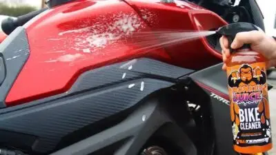 Cleaning a red motorcycle with Monkey Juice bike cleaner spray for a shiny finish. Perfect solution for bike maintenance.