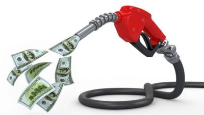 Gas pump nozzle with flowing dollar bills, illustrating rising fuel costs and economic impact.