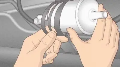 Hands installing a fuel filter into a car's fuel line system, ensuring efficient fuel flow for vehicle maintenance.