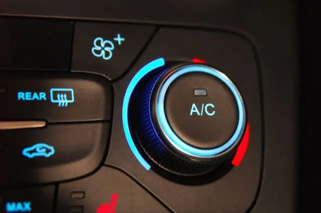 Close-up of a car air conditioning control panel with A/C button and temperature adjustment dial.