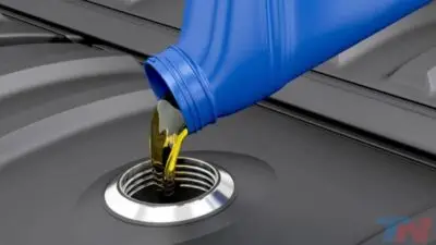 Pouring engine oil into a car, emphasizing maintenance and lubrication for automotive care.