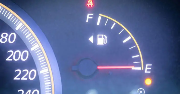 Car fuel gauge showing empty with warning lights on, next to a speedometer.