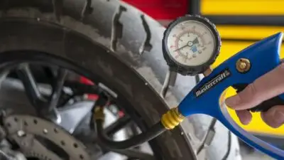 Checking motorcycle tire pressure with a blue gauge for safe rides. Maintain optimal inflation for better performance and longevity.