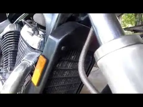 Close-up of a motorcycle engine radiator with metal details and a visible coolant hose, showcasing mechanical components.