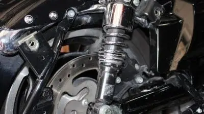 Close-up of a motorcycle rear shock absorber, showcasing detailed components and shiny metal finish. Ideal for automotive enthusiasts.