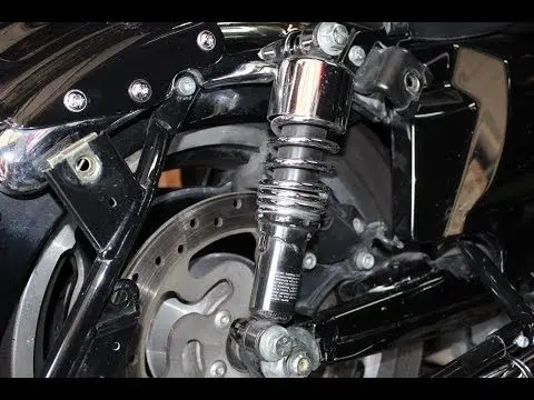 Close-up of a motorcycle rear shock absorber, showcasing detailed components and shiny metal finish. Ideal for automotive enthusiasts.