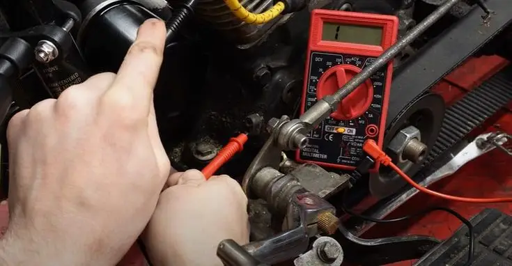 Hands using a digital multimeter to test an engine's electrical system, ensuring proper voltage and functionality.