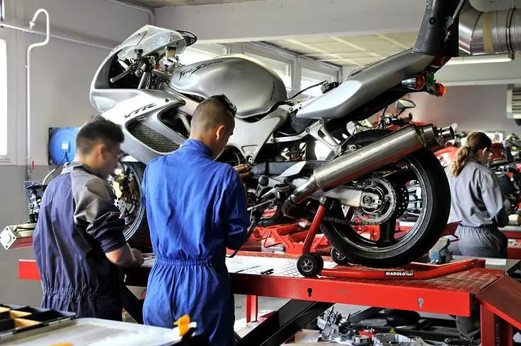 Mechanics working on a motorcycle in a garage, focusing on repairs and maintenance.
