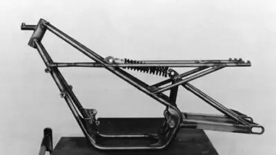 Vintage motorcycle frame with suspension system, showcasing classic engineering design in black and white. Ideal for history or engineering topics.