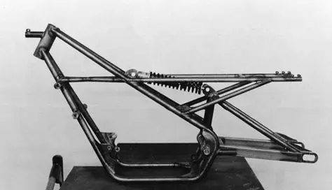 Vintage motorcycle frame with suspension system, showcasing classic engineering design in black and white. Ideal for history or engineering topics.