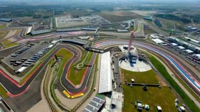 Aerial view of a complex racing circuit showcasing winding tracks and grandstands, set in a vast open landscape under a clear sky.