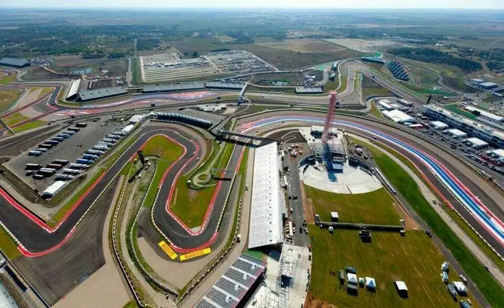 Aerial view of a complex racing circuit showcasing winding tracks and grandstands, set in a vast open landscape under a clear sky.