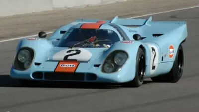 Vintage Gulf-liveried race car on track, showcasing classic design and speed in motorsport competition.