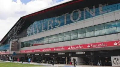 Race track garage at Silverstone Circuit, with bright sky above and people walking by, highlighting motorsport ambiance.