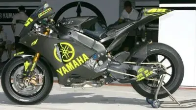 Yamaha race motorcycle with striking black and yellow design, displayed in a garage setting, ready for high-speed performance.
