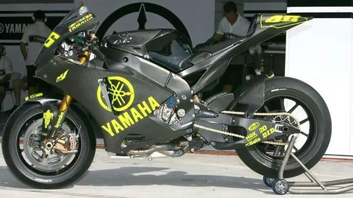 Yamaha race motorcycle with striking black and yellow design, displayed in a garage setting, ready for high-speed performance.
