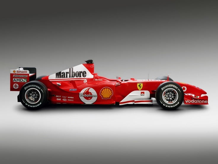 Red Formula 1 race car, branded with Marlboro, Shell, and Ferrari logos, side view on gray background.