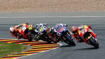 Motorcycle racers leaning into a sharp curve on the track during a competitive race, showcasing speed and precision.
