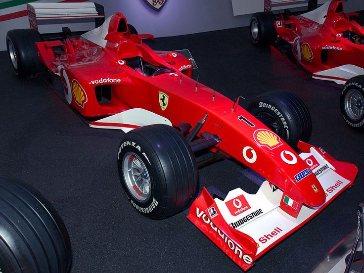 Red Formula 1 Ferrari race car with sponsors on display, showcasing sleek design and advanced aerodynamics.