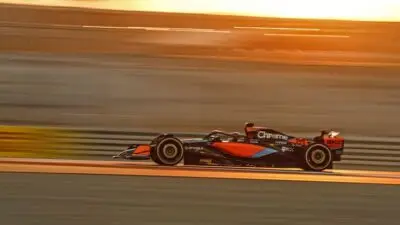 Formula 1 car speeding on track at sunset, emphasizing speed and motion against a golden sky backdrop.