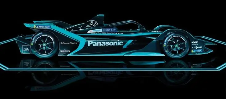 Jaguar Formula E race car in sleek black and teal design, side view with Panasonic branding, reflecting on shiny surface.