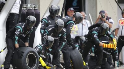 Pit crew changes tires during a Formula 1 race, showcasing teamwork and precision in high-speed motorsport.