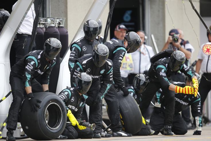 Pit crew changes tires during a Formula 1 race, showcasing teamwork and precision in high-speed motorsport.