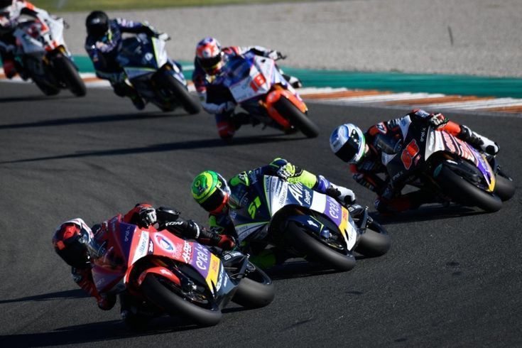 Motorcycle racers speeding on a track, competing closely in a thrilling race.