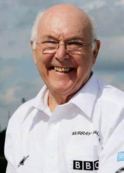 Man in white BBC shirt smiling outdoors on a sunny day, capturing a moment of joy and positivity.