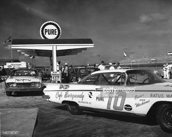 Vintage race cars refuel at a Pure gas station during a classic auto race, highlighting 1960s racing culture and sponsorship.