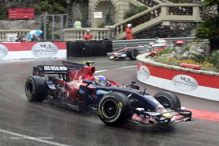 Formula 1 cars racing in the rain at the Monaco Grand Prix, showcasing speed and precision on a challenging circuit.