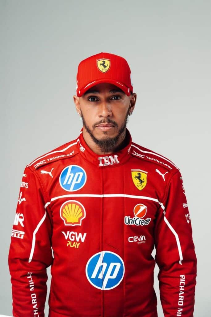 Race car driver in Ferrari suit and cap, showcasing sponsor logos like HP, Shell, and Puma, against a neutral background.