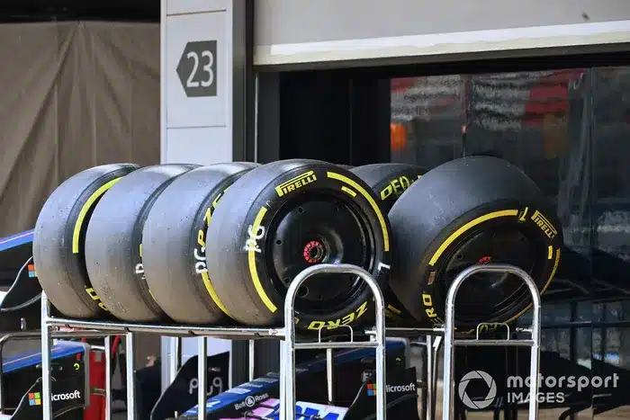 Racing tires stacked on metal carts in a garage, marked with Pirelli branding, ready for a motorsport event.