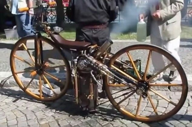 Vintage steam-powered bicycle with wooden wheels on a cobblestone street, emitting light smoke.