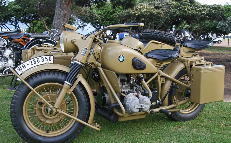 Vintage BMW military motorcycle with sidecar displayed on grass, showcasing classic design and engineering.