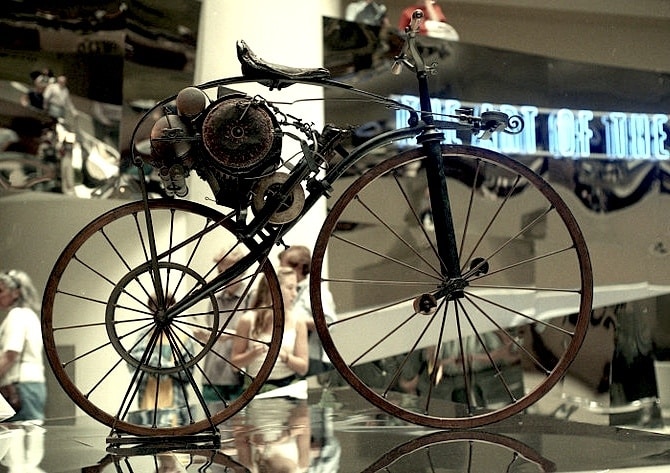 Vintage motorized bicycle on display in a museum, showcasing early innovation in bicycle design with a retro aesthetic.