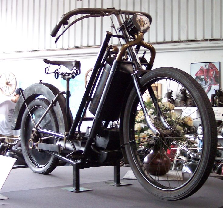 Vintage motorized bicycle on display in a museum, showcasing early transportation technology with a classic black frame and unique design.
