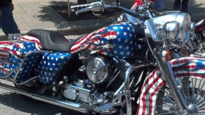 Patriotic motorcycle with American flag design on a sunny street, showcasing chrome details and vibrant colors.