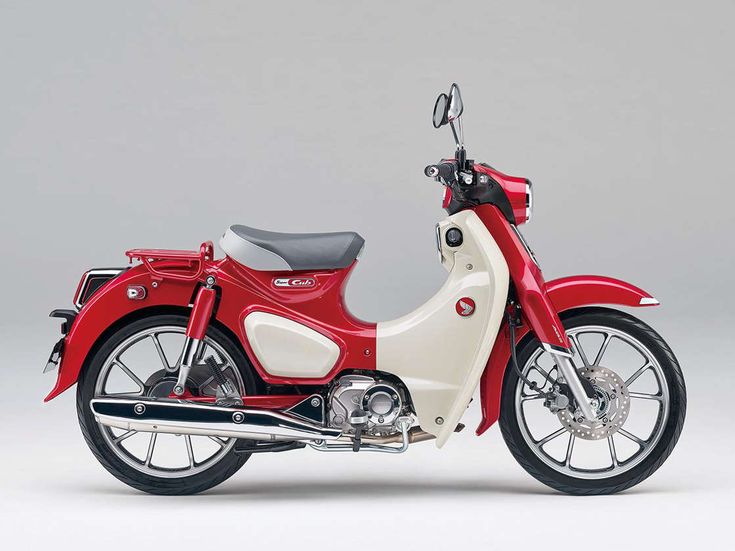Red and white vintage-style motorbike on a gray background, showcasing a classic design with modern elements.